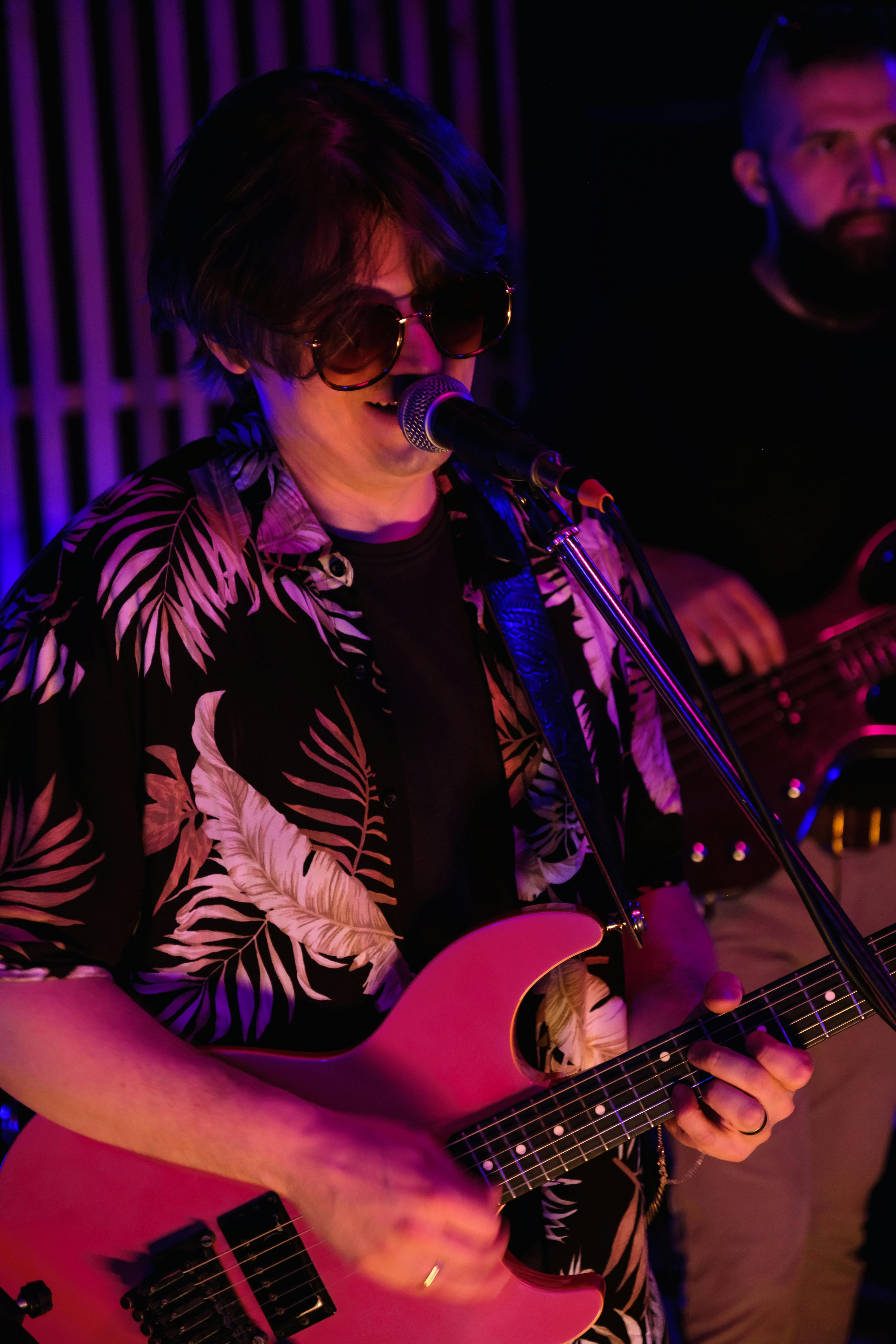Vocalist singing with pink guitar in close-up, performing with intensity